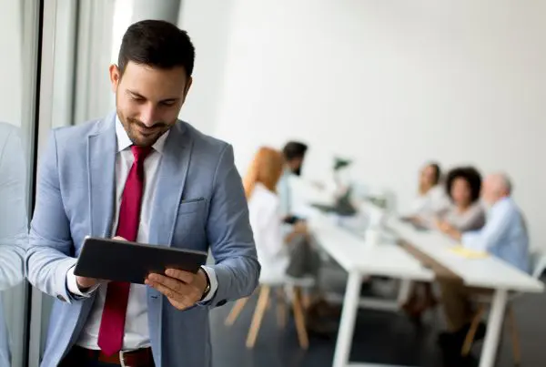 Mann in Anzug steht und nutzt Tablet.